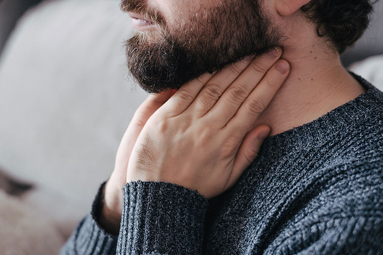 A man holding his throat because he is having trouble swallowing