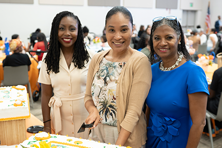 Drs. Bennett and Anderson-Rhodes with attendee cutting congratulations cake