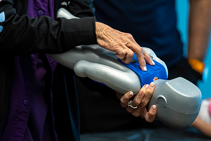 Perinatal educator demonstrating infant CPR on baby simulator