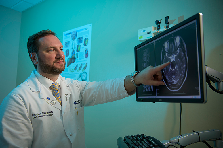 Dr. Christopher DeMassi pointing at a brain scan on a monitor